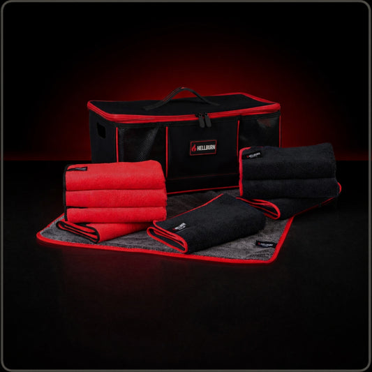 HELLBURN Fahrzeugpflege-Set mit schwarzer Aufbewahrungsbox und Mikrofasertüchern. Enthalten sind ein graues PAINT-Trockentuch, schwarze WHEELS-Tücher und rote ALLROUNDER-Tücher. Premium Produktaufnahme auf dunklem Hintergrund mit roten Akzenten.