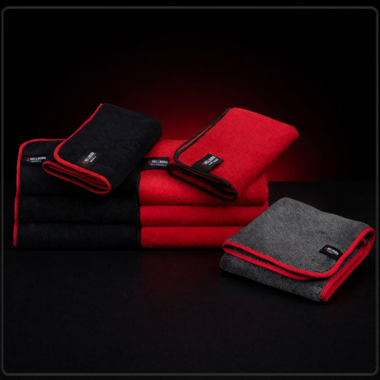 HELLBURN Mikrofasertücher in Rot, Schwarz und Dunkelgrau, gestapelt auf dunklem Studiohintergrund mit rotem Glow.